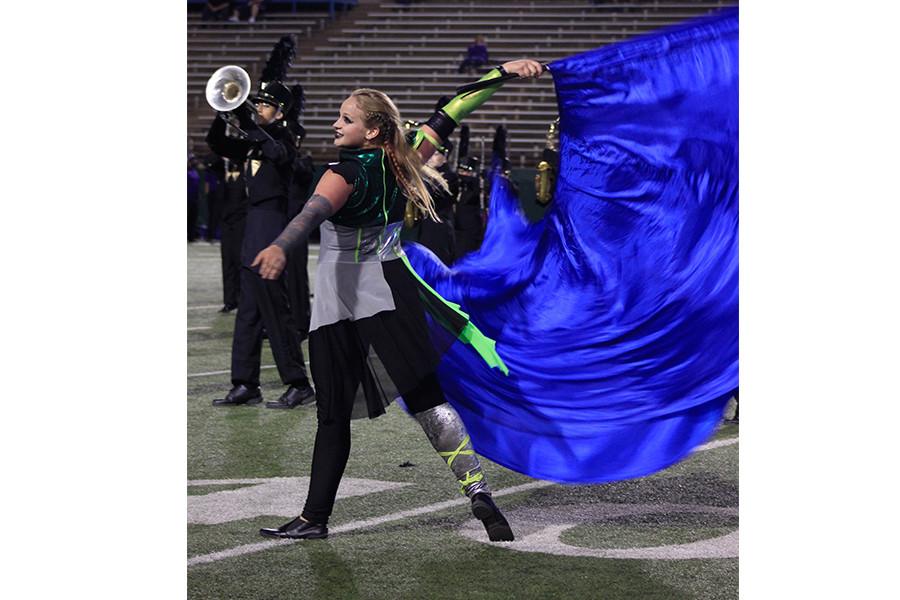 Blue swing flags spin through the air during a halftime performance as senior Molly Whitaker performs. “It’s really fun performing with swing flags,” she said. “Except for the time I got the silk wrapped around my neck and almost choked to death during my solo.”