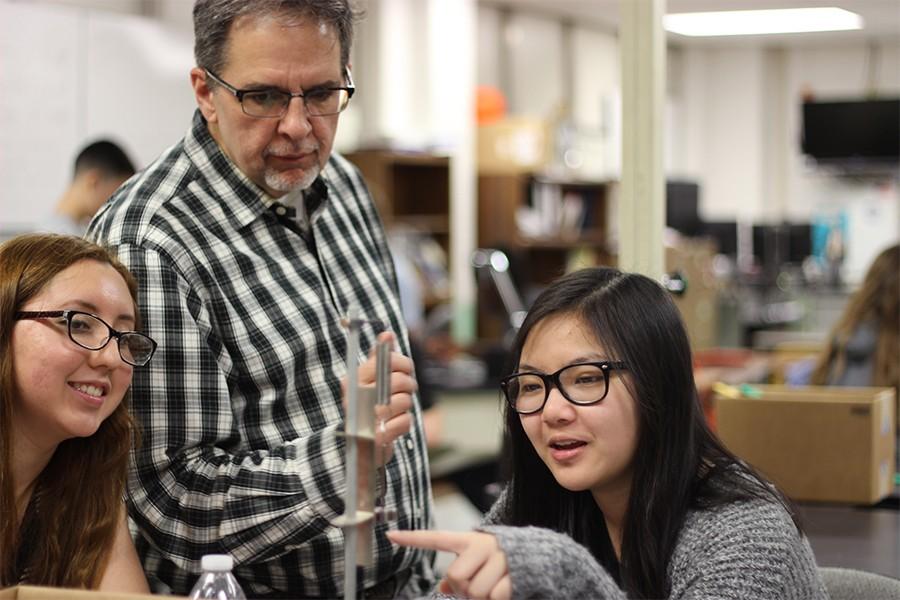 Mr. Baskin watches former students Ashley Flores and Lily Tran complete a lab in AP Physics 1. 