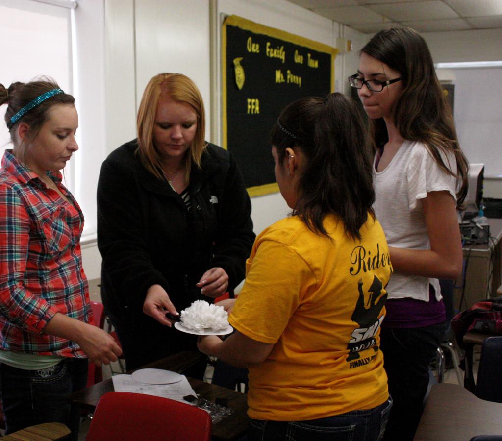 Floral design teacher Ms. Perry teaches her students how to properly assemble a Homecoming mum to be worn in November on Mum Day.