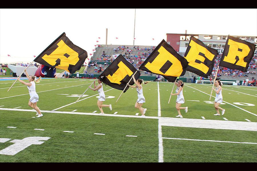 After a touchdown at the game against Abliene Cooper the cheerleaders take the flags that spell Rider and run them across the field on Aug. 28, 2014. The final score was Rider 21 Abliene Cooper 7.