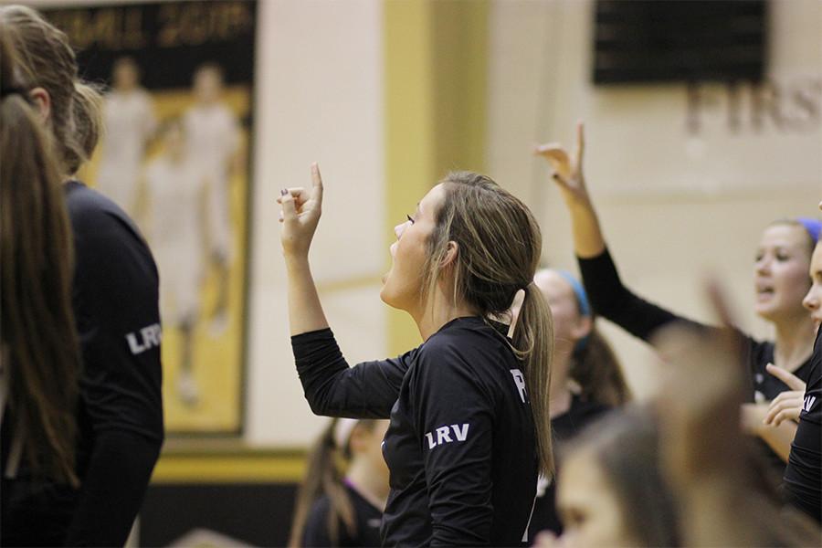 At the game against Old High, senior Libby Nelson holds a one in the air, cheering her team on as varsity only needs one point to win the match.