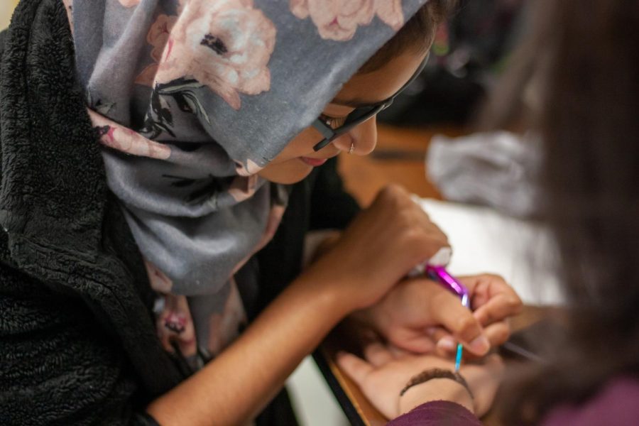 Senior Aribah Tahir draws a personalized pattern with henna for her client. 