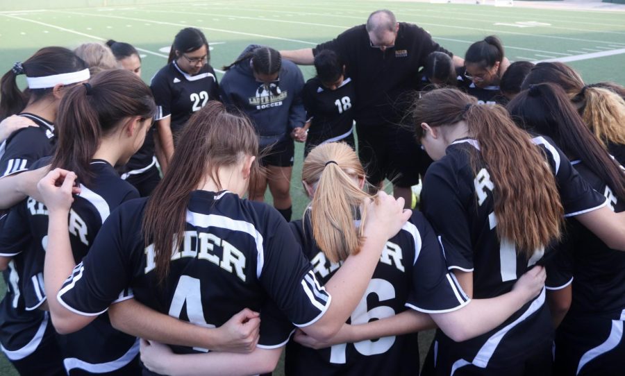 Before the game starts, the junior varsity B girls soccer team huddles together.