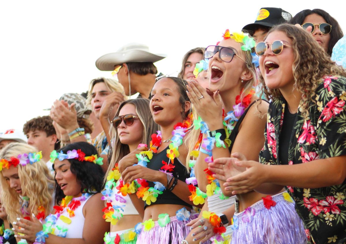 Rider students Reese Wood, Bella Pillow, and Emma Wahl cheer on the Raiders during a home football game.