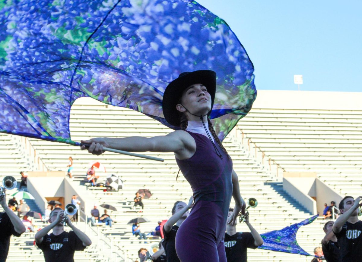 Delaney Bruce waves her flag during an October performance. Color guard tryouts for Legacy and Memorial will be May 13-16. 