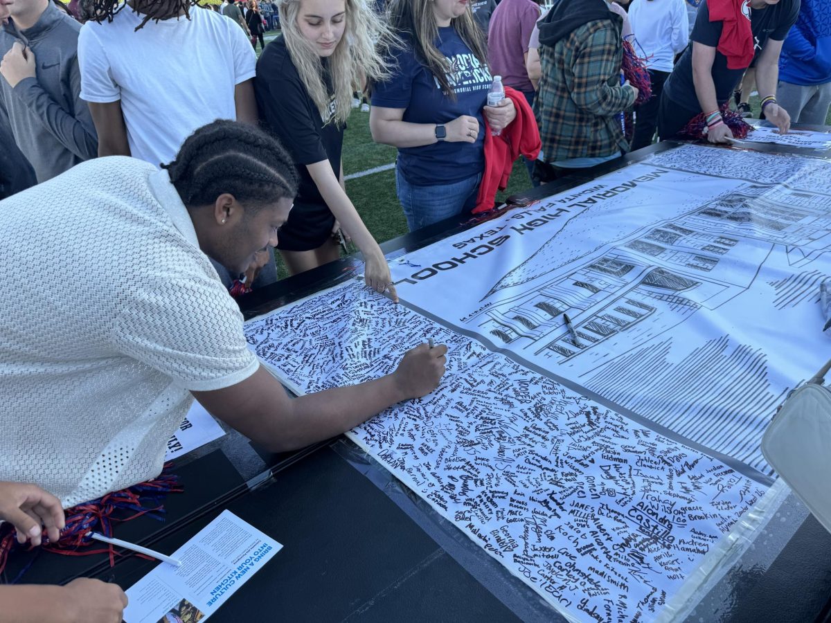 Rider junior Kenji Johnson signs the banner at last weeks Memorial High School event. 